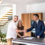 Senior couple signing house leasing agreement and shaking hands with asian real estate agent